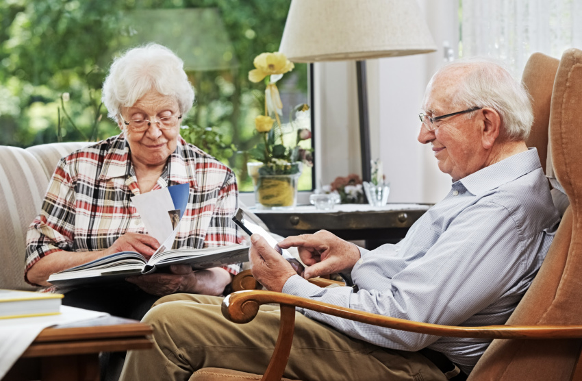 Een ouder echtpaar zit samen aan een tafel met papieren en een laptop, zoekend naar informatie over huurtoeslag.