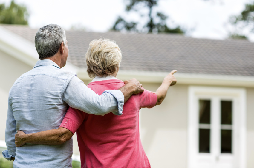 Een echtpaar staat buiten en wijst naar een kangoeroewoning, overwegend om erin te gaan wonen.
